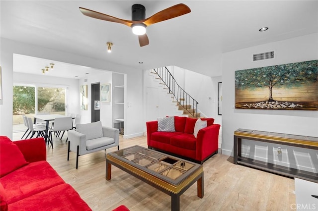 living room featuring ceiling fan, built in shelves, and hardwood / wood-style floors