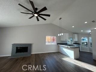 kitchen with ceiling fan, a fireplace, kitchen peninsula, hanging light fixtures, and white cabinets