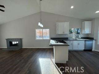 kitchen with decorative light fixtures, white cabinetry, stainless steel dishwasher, and vaulted ceiling