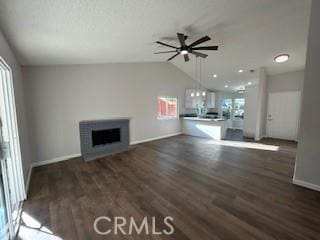 unfurnished living room with vaulted ceiling, ceiling fan, dark hardwood / wood-style flooring, and a fireplace