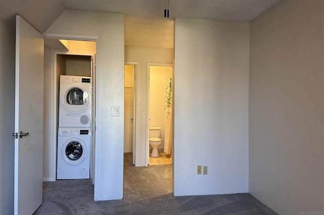 washroom with dark colored carpet and stacked washer / dryer