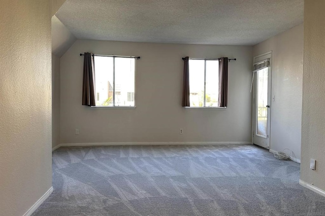 spare room featuring a textured ceiling, vaulted ceiling, and carpet flooring