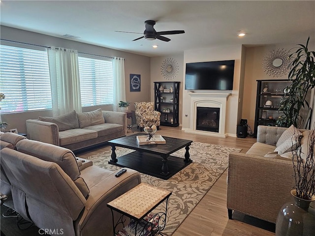 living room with light wood-type flooring, ceiling fan, and plenty of natural light