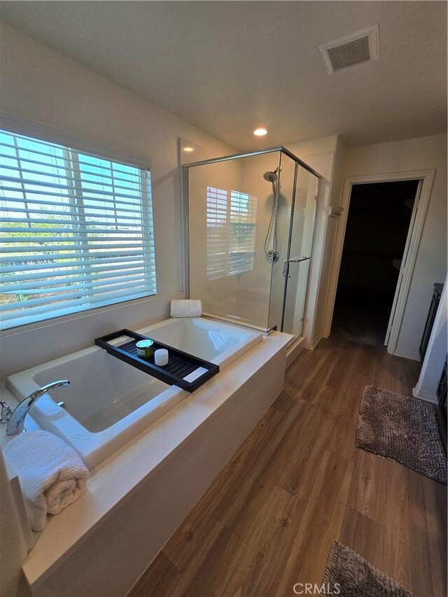 bathroom with hardwood / wood-style flooring and independent shower and bath