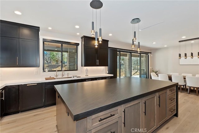 kitchen with a kitchen island, light hardwood / wood-style floors, pendant lighting, sink, and a healthy amount of sunlight