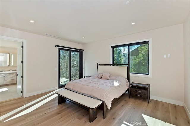 bedroom featuring light wood-type flooring, connected bathroom, and access to outside