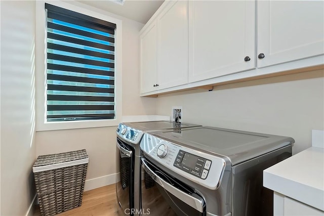 clothes washing area featuring cabinets, washer and clothes dryer, and light wood-type flooring