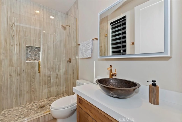 bathroom featuring a shower with shower door, toilet, and vanity