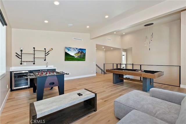 rec room featuring light hardwood / wood-style floors, vaulted ceiling, and wine cooler