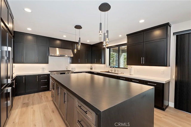 kitchen with sink, hanging light fixtures, light wood-type flooring, and a kitchen island