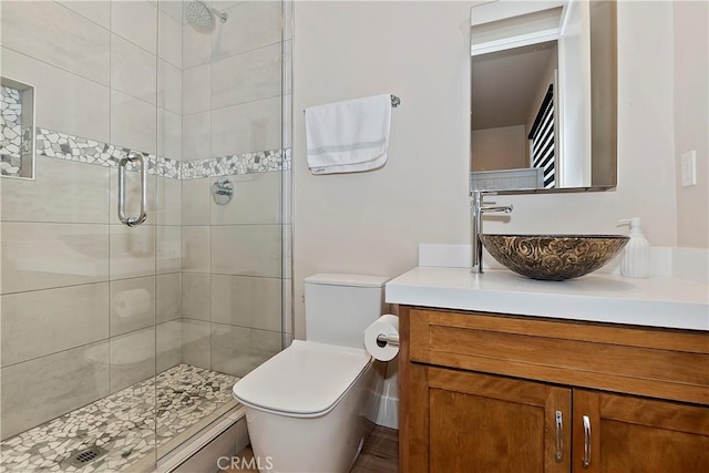 bathroom featuring toilet, a shower with door, and vanity