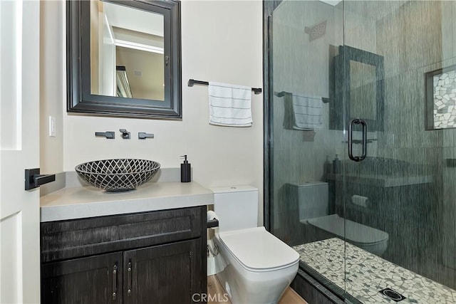 bathroom featuring toilet, a shower with door, and vanity