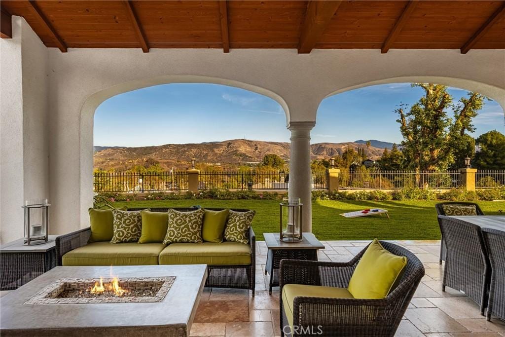 view of patio with a mountain view and an outdoor living space with a fire pit