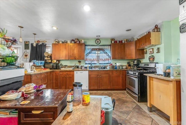 kitchen featuring sink, dishwasher, stainless steel gas stove, light tile patterned flooring, and decorative light fixtures