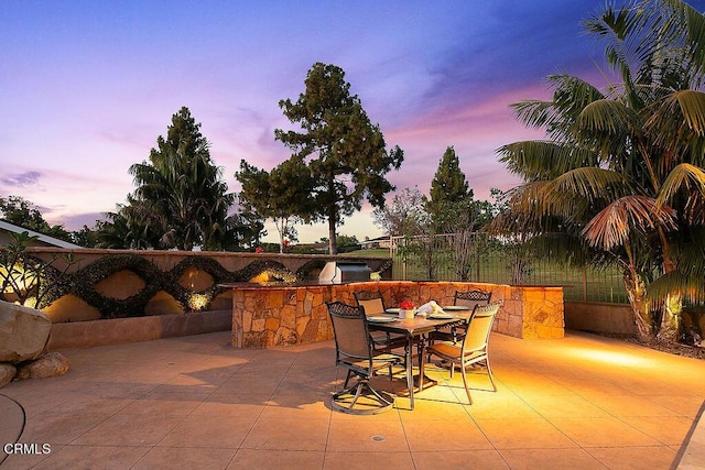 patio terrace at dusk featuring exterior kitchen