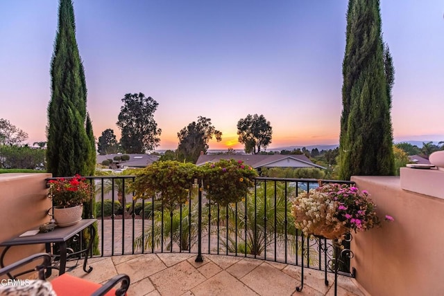 patio terrace at dusk featuring a balcony