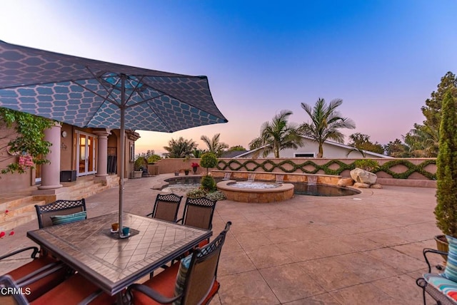 patio terrace at dusk featuring a jacuzzi