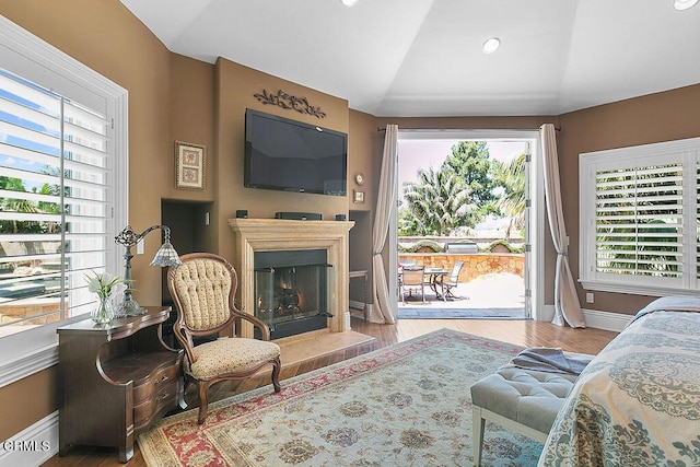 bedroom with vaulted ceiling, hardwood / wood-style floors, and access to outside