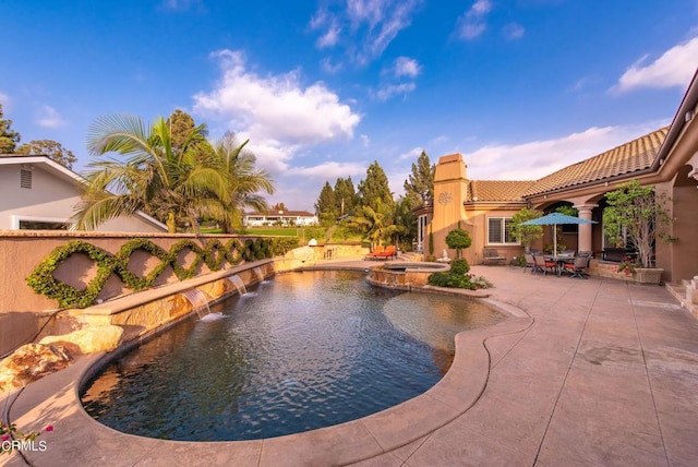 view of swimming pool with pool water feature, a patio, and an in ground hot tub