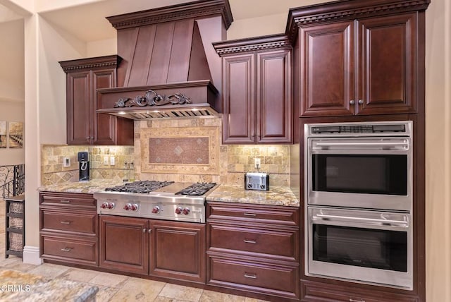 kitchen with premium range hood, appliances with stainless steel finishes, decorative backsplash, and light stone counters