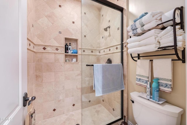 bathroom with a shower with shower door and toilet