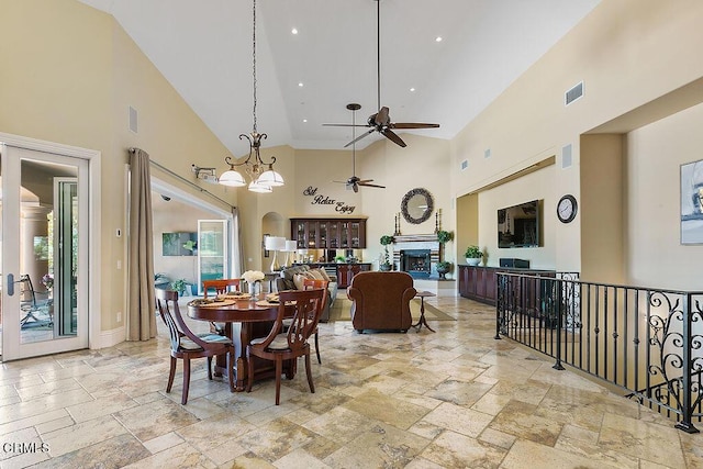 dining area with high vaulted ceiling and ceiling fan with notable chandelier