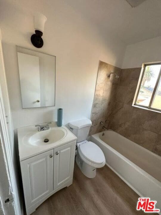 full bathroom with toilet, tiled shower / bath combo, vanity, and hardwood / wood-style flooring