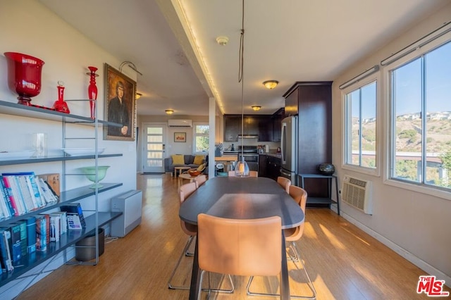 dining area with a wall mounted air conditioner and light wood-type flooring