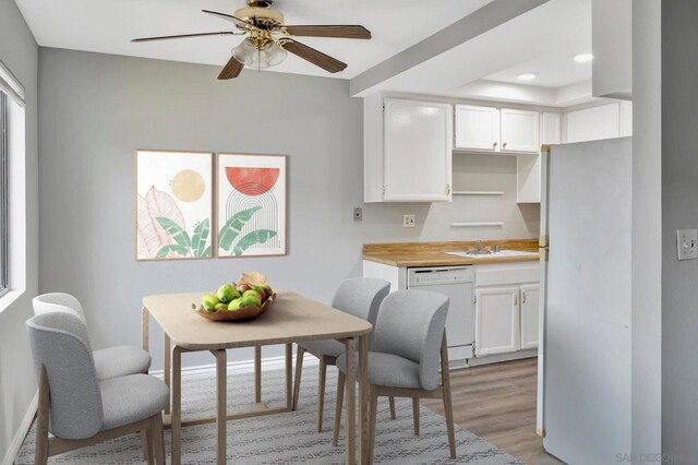 kitchen with white appliances, white cabinets, wood counters, light hardwood / wood-style floors, and sink