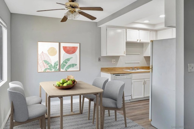 kitchen featuring white cabinetry, light hardwood / wood-style floors, butcher block countertops, white appliances, and sink