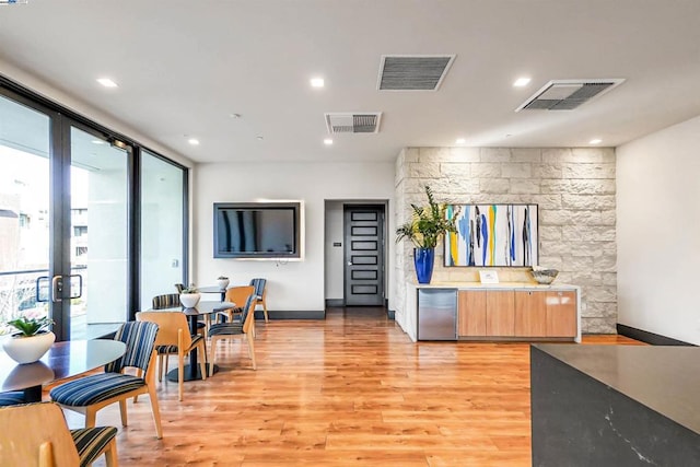 interior space featuring floor to ceiling windows, light brown cabinets, light hardwood / wood-style flooring, and a wealth of natural light