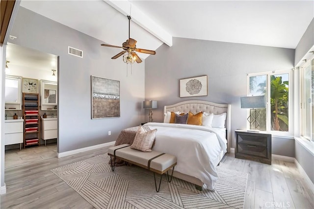 bedroom featuring ceiling fan, ensuite bath, lofted ceiling with beams, and light hardwood / wood-style floors