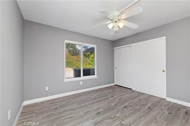 unfurnished bedroom with ceiling fan, a closet, and light wood-type flooring