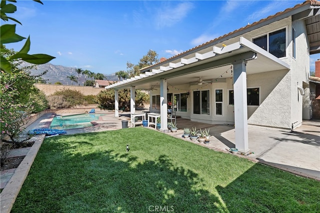 view of yard featuring ceiling fan, a patio area, a mountain view, and a fenced in pool