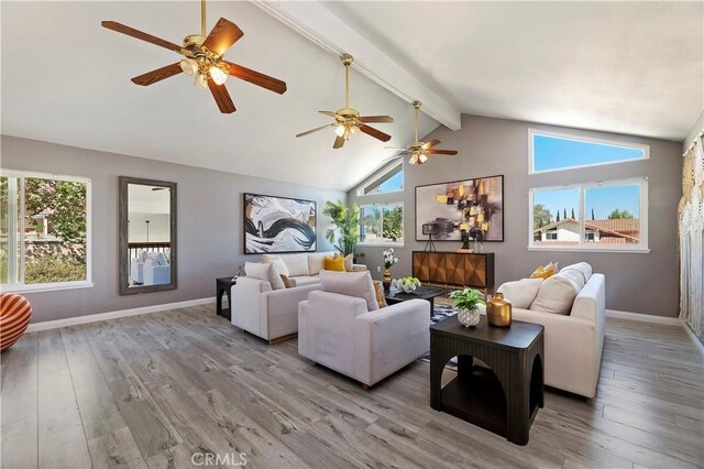 living room with plenty of natural light, light hardwood / wood-style flooring, and vaulted ceiling with beams