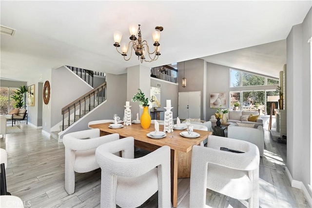 dining area with lofted ceiling, a notable chandelier, and light wood-type flooring