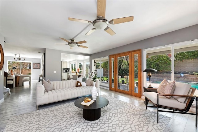 living room with hardwood / wood-style flooring, plenty of natural light, and ceiling fan with notable chandelier