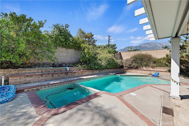 view of swimming pool featuring a patio area, a mountain view, and an in ground hot tub