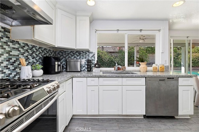 kitchen with white cabinets, appliances with stainless steel finishes, tasteful backsplash, sink, and range hood