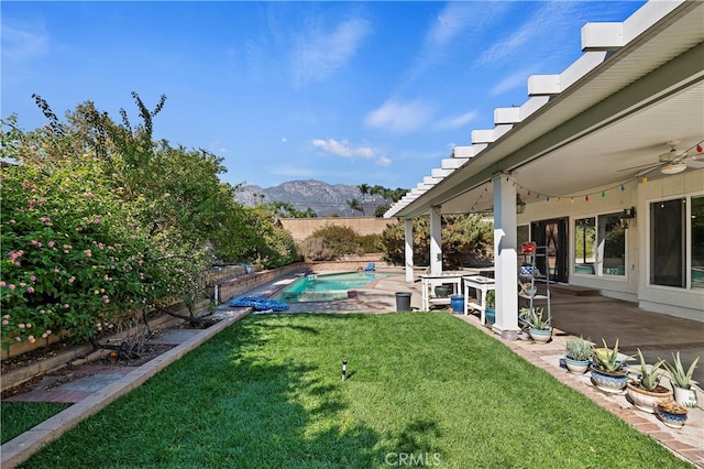 view of yard featuring a mountain view, ceiling fan, and a patio