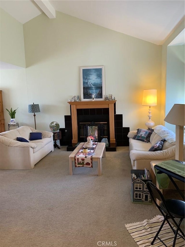 carpeted living room with a tile fireplace and lofted ceiling with beams