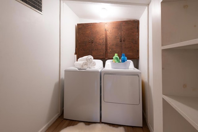 laundry area featuring cabinets, light hardwood / wood-style flooring, and washer and dryer