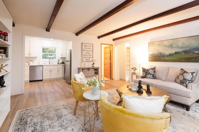 living room featuring beam ceiling, light hardwood / wood-style floors, and sink