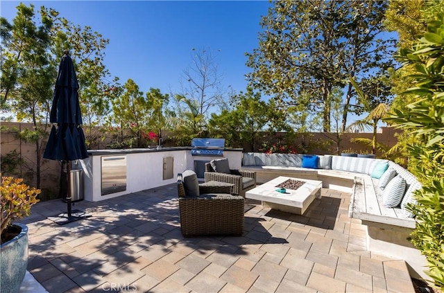 view of patio with exterior kitchen, grilling area, and an outdoor living space with a fire pit