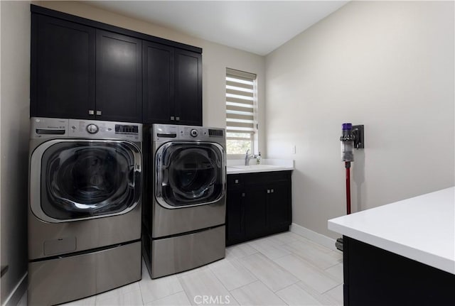 washroom with cabinets, washing machine and clothes dryer, and sink