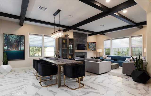 dining room featuring a chandelier, beam ceiling, and a tile fireplace