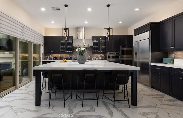 kitchen featuring decorative backsplash, a large island with sink, stainless steel appliances, and pendant lighting