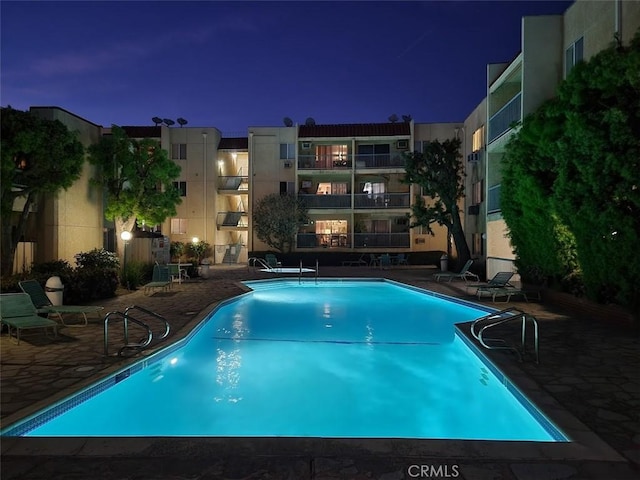 pool at twilight featuring a patio area