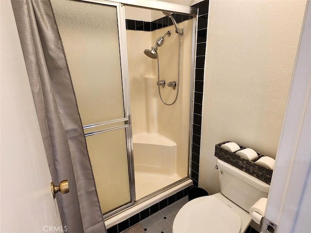 bathroom with an enclosed shower, tile patterned floors, and toilet