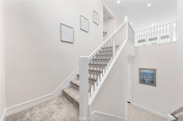 stairs with a high ceiling, recessed lighting, carpet flooring, and baseboards